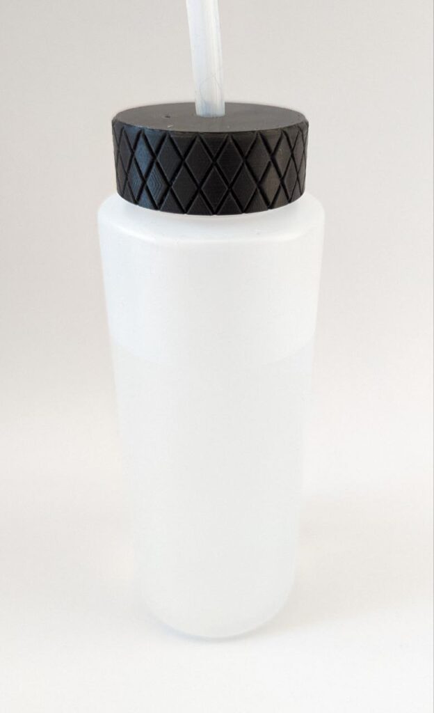 a transparent PE bottle with a black screwed on cap. The cap has a hole where the 3mm silicone tube is fed through.